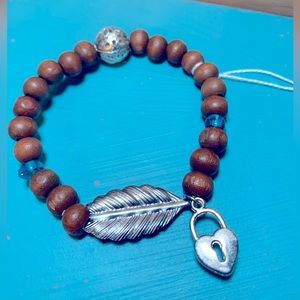 Wood bead bracelet with feather and heart lock. Stretchy one size boho vibe.